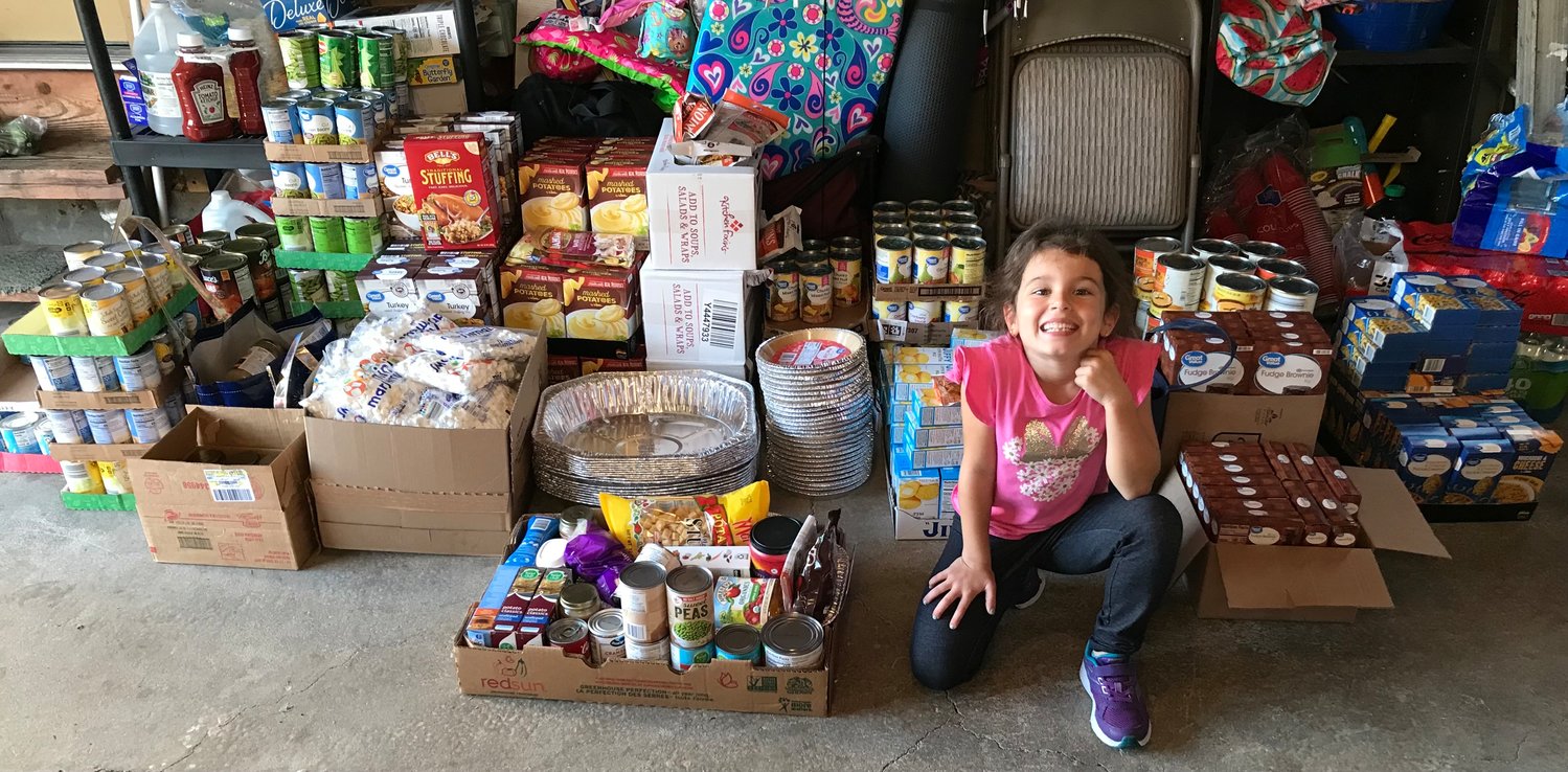 Avery Mattimore sits in front of several boxes, filled with supplies, to bestow Avery’s Birthday Blessings upon children in need.